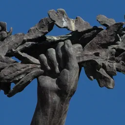 Close-up of the angel's hand raising a wreath against the blue sky.