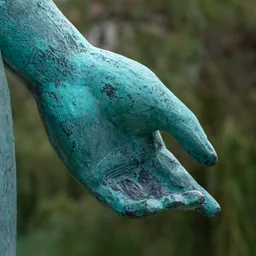 Close-up of the young worker's left hand with green bronze patina.