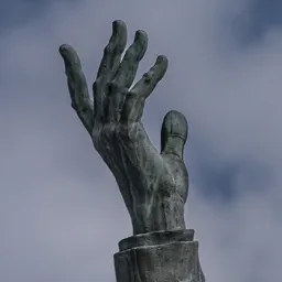 Close-up of Petőfi's raised right hand against the sky.